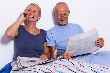 Image showing Senior Couple with Tablet and Newspaper in Bed