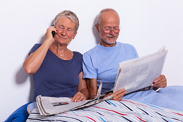 Image showing Senior Couple with Tablet and Newspaper in Bed