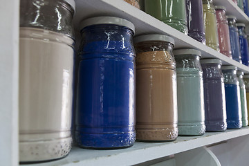 Image showing Shelving with glass jars of colorful pigments