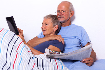 Image showing Senior Couple with Tablet and Newspaper in Bed