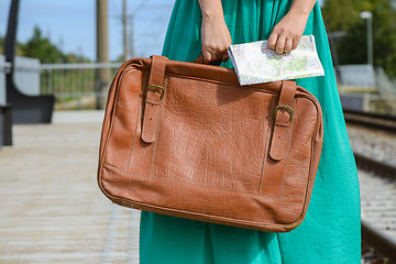 Image showing Girl in a holding a map and suitcase at station