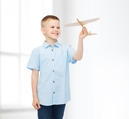 Image showing smiling little boy holding a wooden airplane model