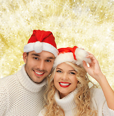 Image showing smiling couple in sweaters and santa helper hats