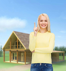 Image showing smiling woman pointing her finger up