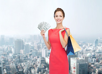 Image showing smiling woman in red dress with shopping bags