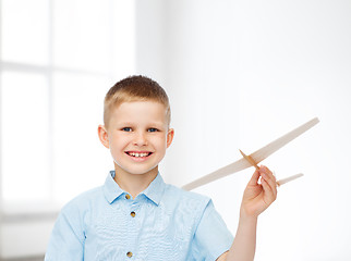 Image showing smiling little boy holding a wooden airplane model