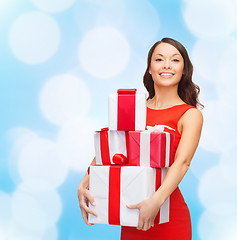 Image showing smiling woman in red dress with gift boxes