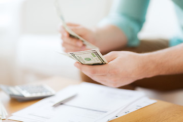 Image showing close up of man counting money and making notes