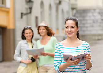 Image showing smiling teenage girls with city guides and camera