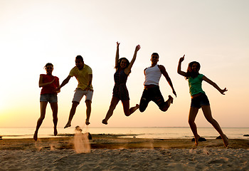 Image showing smiling friends dancing and jumping on beach