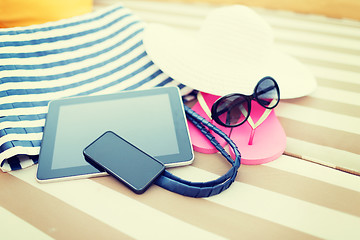 Image showing close up of tablet pc and smartphone on beach