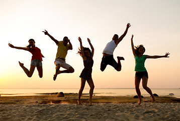 Image showing smiling friends dancing and jumping on beach