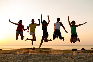 Image showing smiling friends dancing and jumping on beach