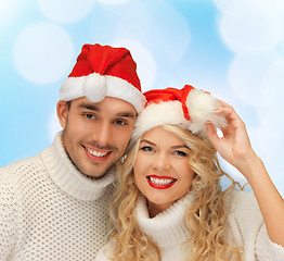 Image showing smiling couple in sweaters and santa helper hats