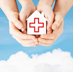 Image showing hands holding paper house with red cross