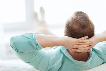 Image showing man lying or sitting on sofa at home from back