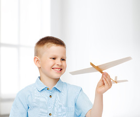 Image showing smiling little boy holding a wooden airplane model