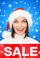 Image showing smiling woman in santa helper hat with sale sign