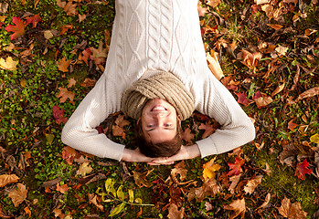 Image showing smiling young man lying on ground in autumn park