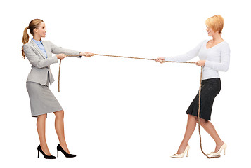 Image showing two smiling businesswomen pulling rope