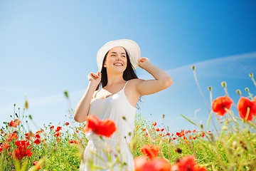 Image showing smiling young woman in straw hat on poppy field