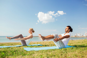 Image showing smiling couple making yoga exercises outdoors