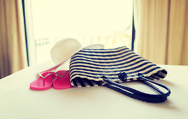 Image showing close-up of beach bag, hat and flip-flop on bed