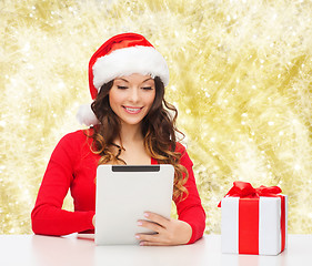 Image showing smiling woman in santa hat with gift and tablet pc