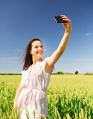 Image showing smiling girl with smartphone on cereal field