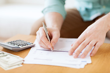 Image showing close up of man counting money and making notes