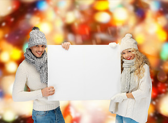 Image showing smiling couple in winter clothes with blank board