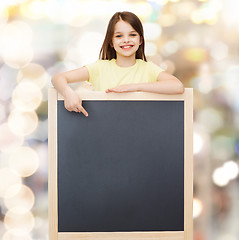 Image showing happy little girl pointing finger to blackboard