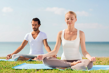 Image showing smiling couple making yoga exercises outdoors