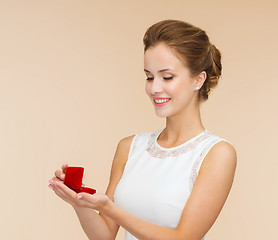 Image showing smiling woman holding red gift box with ring