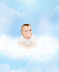 Image showing smiling baby lying on cloud with dummy in mouth