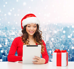 Image showing smiling woman in santa hat with gift and tablet pc