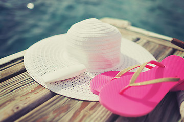 Image showing close up of hat, sunscreen and slippers at seaside