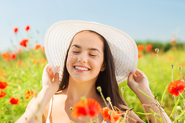 Image showing smiling young woman in straw hat on poppy field