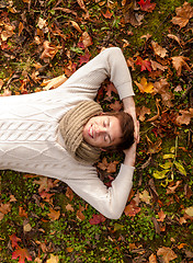 Image showing smiling young man lying on ground in autumn park