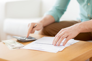 Image showing close up of man counting money and making notes