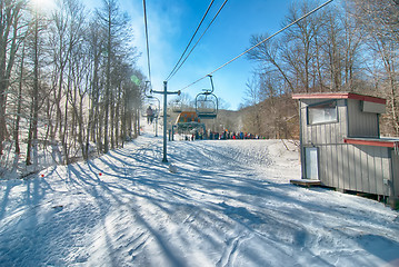 Image showing Ski lift with seats going over the mountain