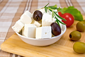 Image showing Feta with olives in cup on brown cloth and board