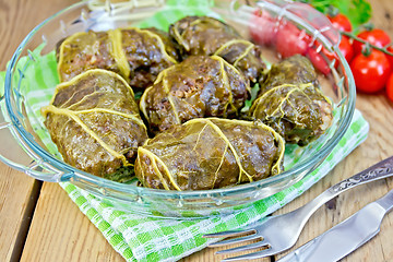 Image showing Rhubarb leaves stuffed in glass dish on board