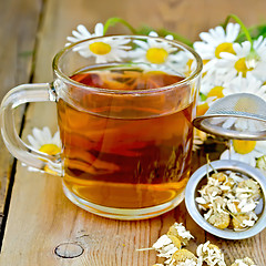 Image showing Herbal chamomile tea in a mug with strainer on the board