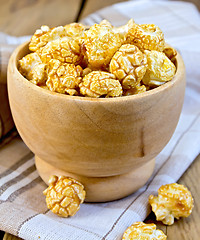 Image showing Popcorn caramel in wooden bowl on board with napkin