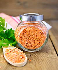 Image showing Lentils red in jar and spoon on board with parsley