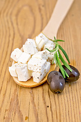Image showing Feta in wooden spoon with olives on board