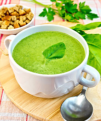 Image showing Soup puree with spinach leaves and spoon on fabric