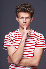 Image showing Hush. Young serious sullen man with finger on lips