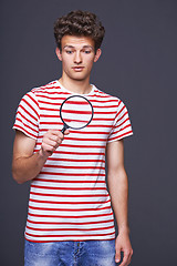 Image showing Astonished man looking through a magnifying glass